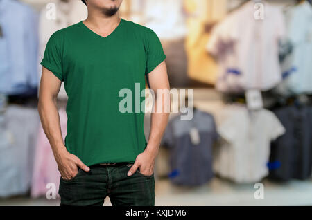 Man wearing blank t-shirt on Abstract blurred photo of clothing store in a shopping mall, shopping concept Stock Photo