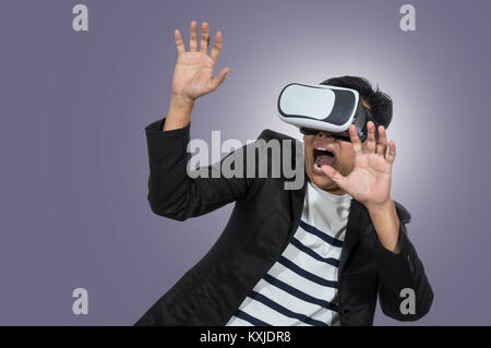 Asian Man wearing virtual reality in scared action on blue background, include clipping path Stock Photo