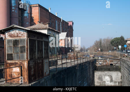 disused industrial buildings on one side of the canal, near Pavia, Italy Stock Photo