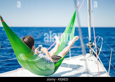 Man in hammock on sail boat Stock Photo