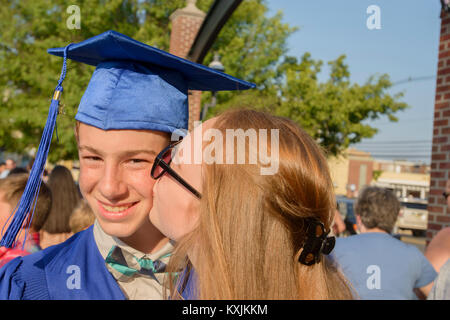 Girl kissing boy on cheek at graduation ceremony Stock Photo