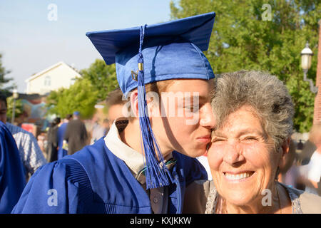 Teenage boy kissing grandmother at graduation ceremony Stock Photo