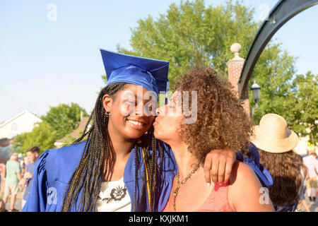 Mother kissing daughter on cheek at graduation ceremony Stock Photo