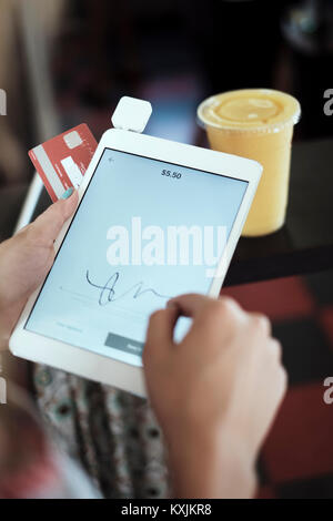 Close up of young woman's hands signing digital tablet Stock Photo