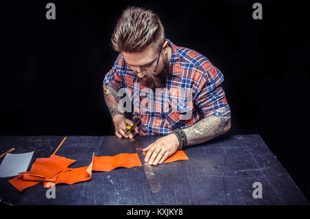 Artisan working with leather makes quality products in his studio Stock Photo