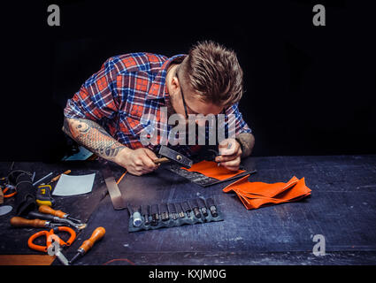 Leather Craftsman demostrating leather cutting process in his leather studio Stock Photo