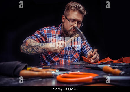 Leather Tanner cuts out leather goods in the work area Stock Photo