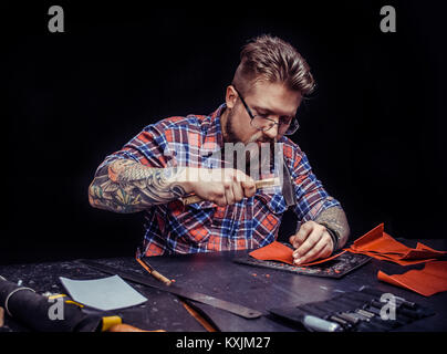 Man working with leather demostrating leather cutting process at his leather shop Stock Photo