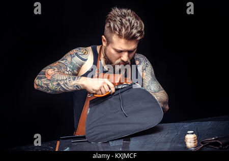 Professional Leather Worker cutting out leather shapes for a new product in his work area Stock Photo