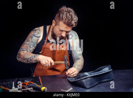 Leather Craftsman creates a new leatherwork at his shop Stock Photo