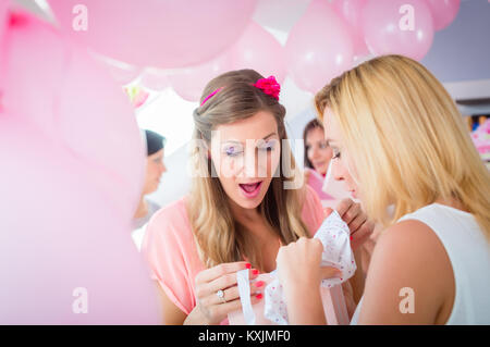 Woman giving gift to pregnant friend on baby shower Stock Photo