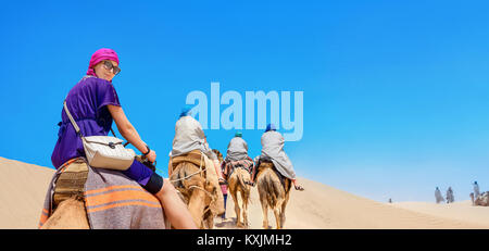 Group of tourists riding on camels. Safari tourism. Sahara desert, Tunisia, North Africa Stock Photo