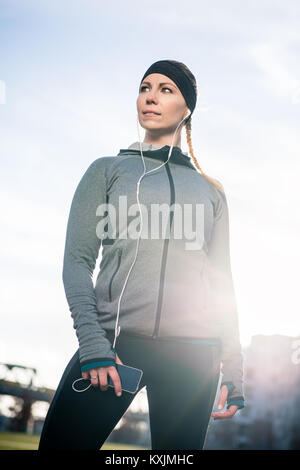 Thoughtful young woman listening to music while wearing trendy s Stock Photo