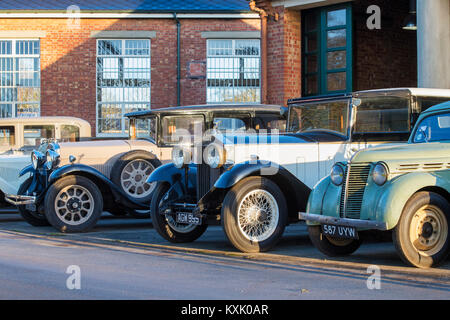 Line of Vintage cars including a 1933 Rolls Royce  outside a garage at Bicester Heritage centre. Bicester, Oxfordshire, England. Stock Photo