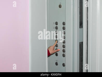 Female hand presses the seventh floor button on the panel of the Elevator when the doors are open Stock Photo