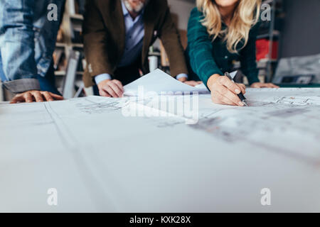 Creative business people working together on real estate projects. Close up of female hand pointing at building drawing. Stock Photo