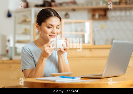 Satisfied young woman sitting and drinking coffee. Stock Photo