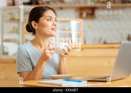 Joyful pretty woman drinking coffee and looking aside. Stock Photo