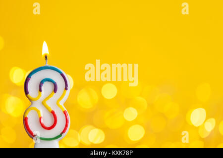 Number 3 birthday celebration candle against a bright lights and yellow background Stock Photo