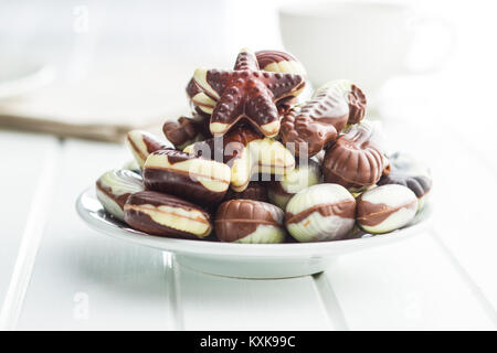 Sweet chocolate seashells on white plate. Stock Photo