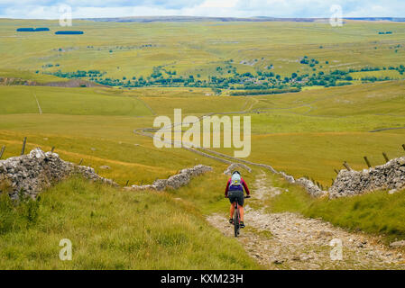 Female mountain biker on the well-known Mastiles Lane in the Yorkshire Dales, descending towards Wharfedale