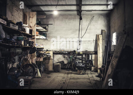 Mechanic sitting in armchair looking at dismantled vintage motorcycle in workshop Stock Photo