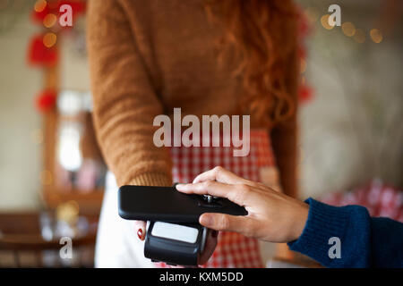 Customer in cafe making contactless payment with mobile phone Stock Photo