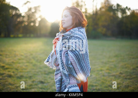 Young woman in rural setting,wrapped in blanket Stock Photo