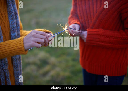 Two young women,in rural setting,lighting sparklers,mid section Stock Photo