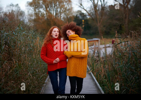 Two young women,walking arm in arm along rural pathway Stock Photo