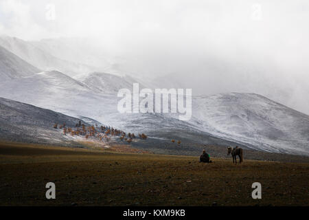 Goat keeper shepherd horse rider resting Mongolian winter snowy mountains Stock Photo