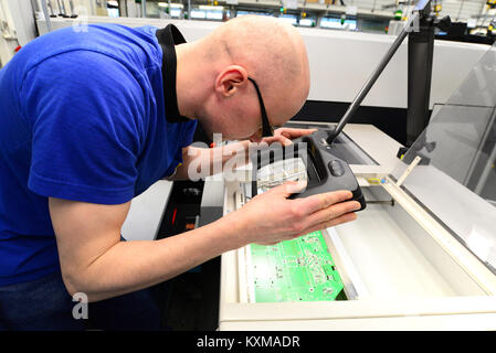 quality control in the production - man checks board for defects - manufacturing in a high tech factory Stock Photo