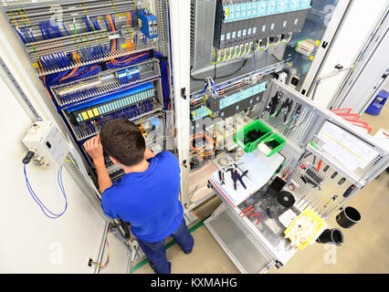 man assembles electronic components on a machine in a factory for mechanical engineering Stock Photo