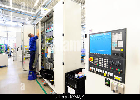 man assembles electronic components on a machine in a factory for mechanical engineering Stock Photo