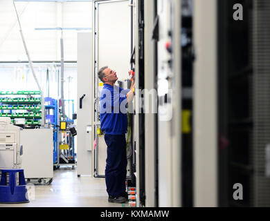 man assembles electronic components on a machine in a factory for mechanical engineering Stock Photo