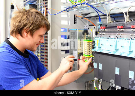 man assembles electronic components on a machine in a factory for mechanical engineering Stock Photo