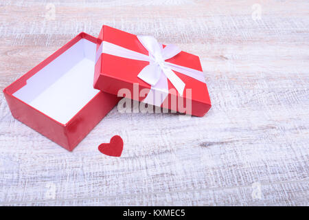 Red gift box with ribbon bow opened on vintage white wooden table Stock Photo