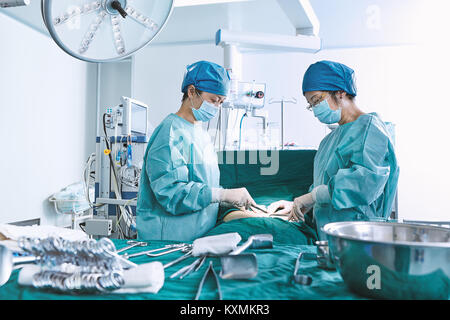 Surgeons performing surgery on patient abdomen in maternity ward operating theatre Stock Photo