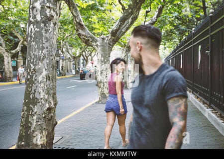 Young male hipster and woman looking back on sidewalk,Shanghai French Concession,Shanghai,China Stock Photo