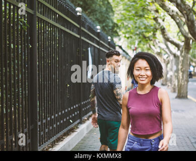 Young male hipster looking back at woman on sidewalk,Shanghai French Concession,Shanghai,China Stock Photo