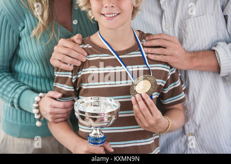 Cropped view of boy proudly holding trophy and medal Stock Photo