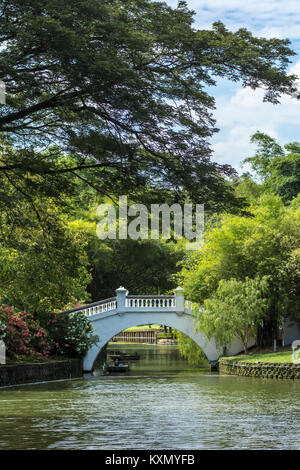 Chinese asian style concrete white footbridge over river in public oriental gardens on sunny day. Stock Photo