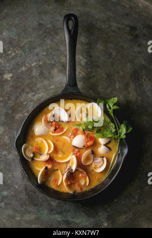 Vongole in tomato cream sauce for pasta in cast-iron pan over old metal texture background. Top view, space Stock Photo
