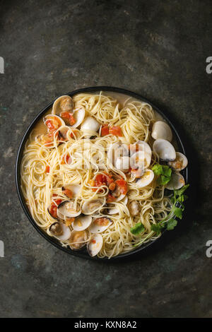 Pasta spaghetti Vongole in tomato cream sauce in black plate over old metal texture background. Top view, space Stock Photo