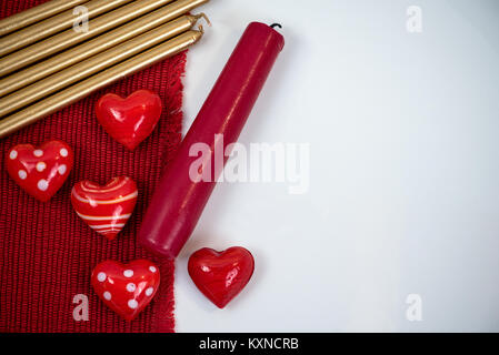 Small red heart figurines made of glass, red and gold candles isolated on white background Stock Photo