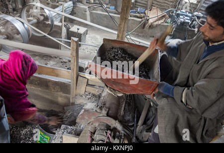 December 23, 2017 - Kolhom, Jammu and Kashmir, India - A Kashmiri man grinds water chestnuts to obtain flour at a mill on January 05, 2018 in Kolhom, north of Srinagar, the summer capital of Indian Administered Kashmir, India. Water chestnuts are a major crop for people living near Wular lake, Asia's second largest freshwater lake. Wular, looks more like a flat marshy plain than a large lake in winters, as the water level recedes entire families collect and extract the marble-sized fruit from its spiky casing . The sun-dried chestnuts are later sold in markets, particularly in summer ca Stock Photo