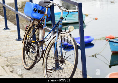 Old bicycle / bike resting on railings at a quayside / waterfront in Concarneau, Brittany, France Stock Photo