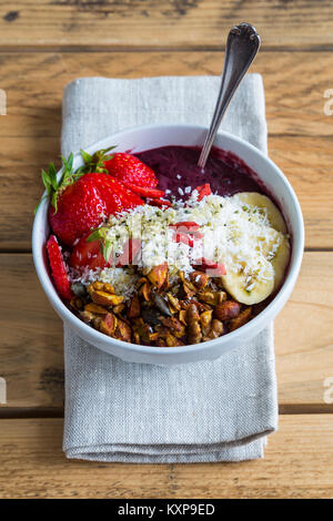 Acai bowl on napkin - Bowl of acai purée with toppings of banana, strawberry, granola and seeds. Stock Photo