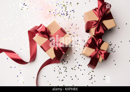 top view of arranged gifts with red ribbons and confetti isolated on white Stock Photo