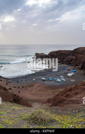 wild beach on the Atlantic Ocean in El Golfo village. A rocky beach with fishing boats surrounded by volcanic mountains Stock Photo